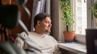 independent adult sitting next to window seal in room